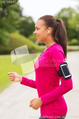 Image of smiling young woman running outdoors