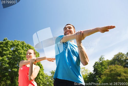 Image of smiling couple stretching outdoors