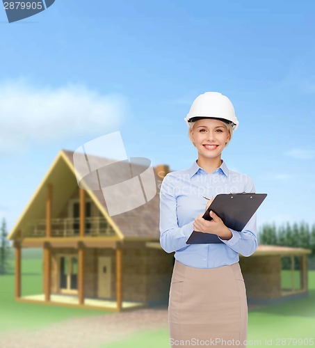 Image of smiling businesswoman in helmet with clipboard