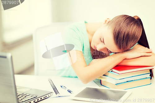 Image of tired student sleeping on stock of books