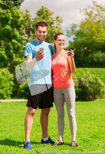 Image of two smiling people with smartphones outdoors