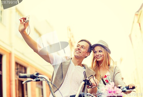 Image of couple with bicycles taking photo with camera