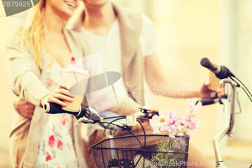 Image of couple holding coffee and riding bicycle