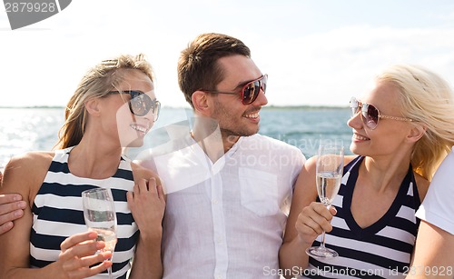 Image of smiling friends with glasses of champagne on yacht