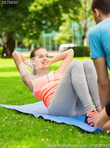 Image of smiling woman doing exercises on mat outdoors