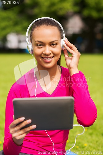 Image of smiling woman with tablet pc outdoors