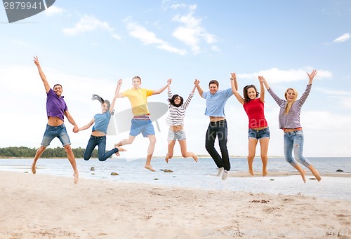 Image of group of friends jumping on the beach