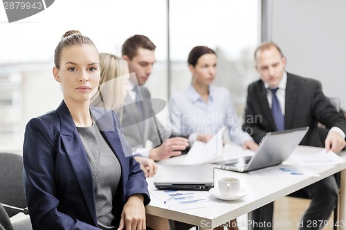 Image of businesswoman in office with team on the back