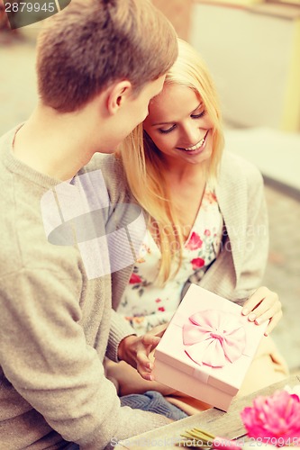 Image of romantic happy couple with gift in the cafe