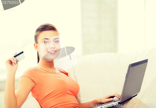 Image of woman with laptop showing credit card at home