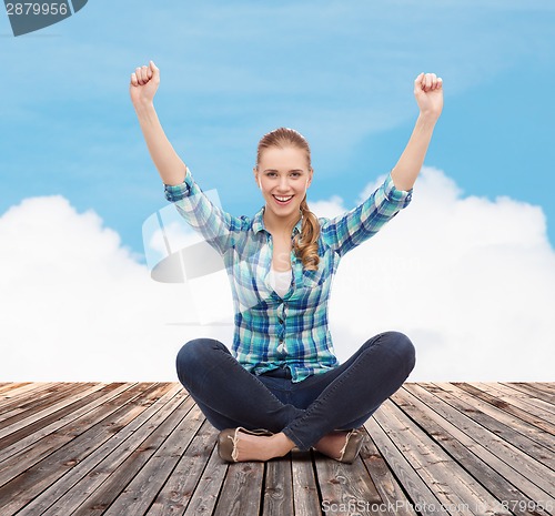 Image of young woman in casual clothes sitting on floor
