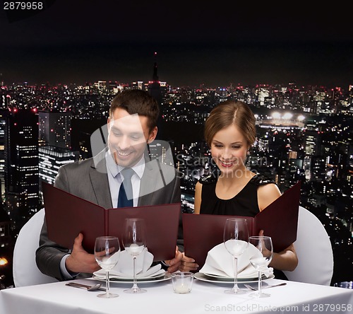 Image of smiling couple with menus at restaurant