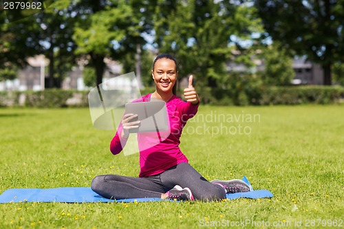 Image of smiling woman with tablet pc showing thumbs up