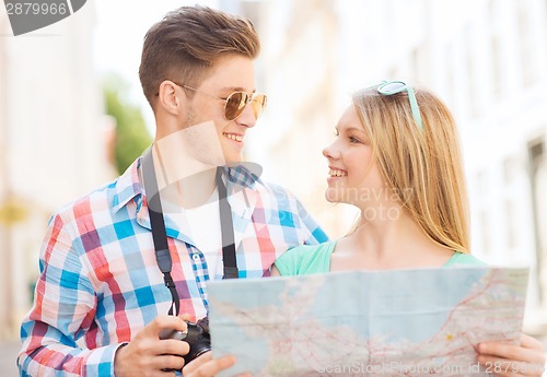 Image of smiling couple with map and photo camera in city