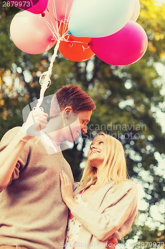 Image of smiling couple with colorful balloons in park