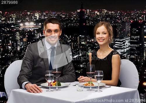 Image of smiling couple eating main course at restaurant