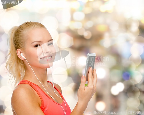 Image of smiling sporty woman with smartphone and earphones