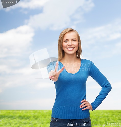 Image of smiling teenage girl showing v-sign with hand