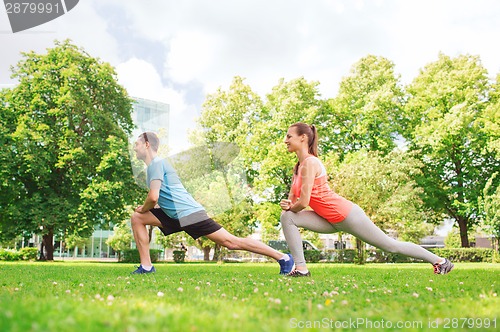 Image of smiling couple stretching outdoors