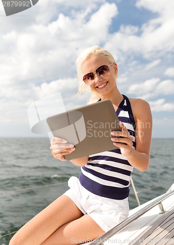 Image of smiling woman sitting on yacht with tablet pc