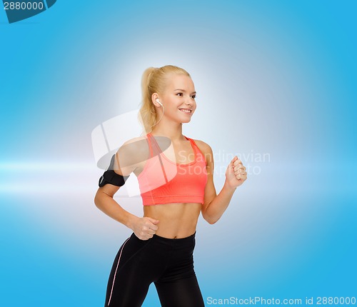 Image of sporty woman running with smartphone and earphones