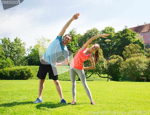 Image of smiling couple stretching outdoors