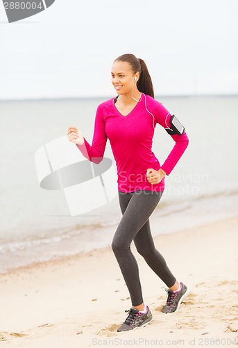Image of smiling woman running on track outdoors