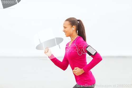 Image of smiling young woman running outdoors