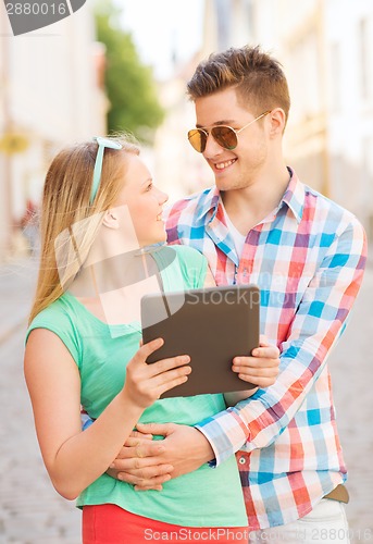 Image of smiling couple with tablet pc in city