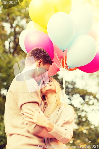 Image of smiling couple with colorful balloons in park