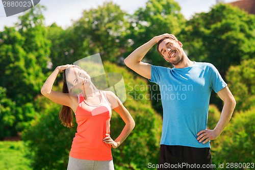 Image of smiling couple stretching outdoors