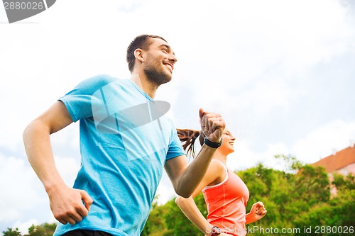 Image of smiling couple running outdoors
