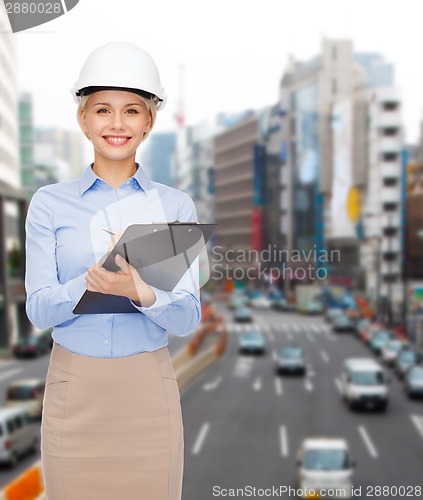 Image of smiling businesswoman in helmet with clipboard