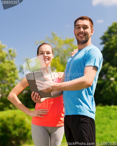 Image of smiling couple with tablet pc outdoors