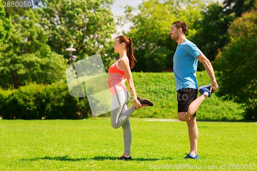 Image of smiling couple stretching outdoors