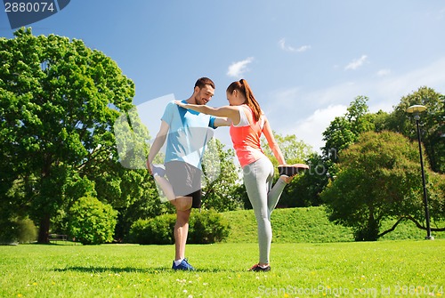 Image of smiling couple stretching outdoors