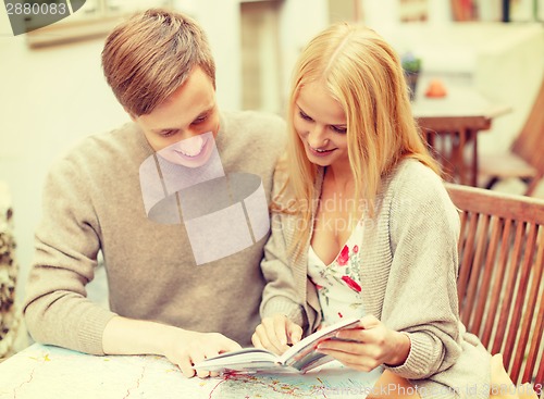 Image of couple with map, camera and city guide in cafe