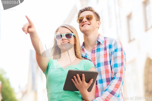 Image of smiling couple with tablet pc in city