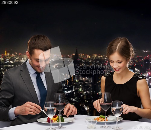 Image of smiling couple eating main course at restaurant