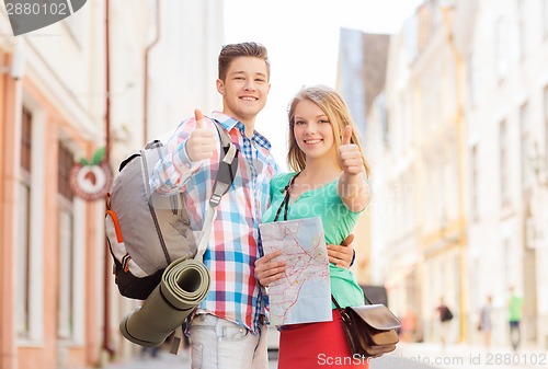 Image of smiling couple with map and backpack in city