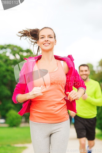 Image of smiling couple running outdoors