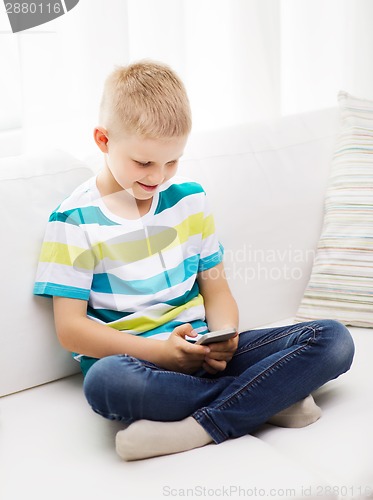 Image of smiling little boy with smartphone at home
