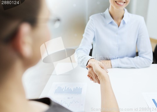 Image of two smiling businesswoman shaking hands in office