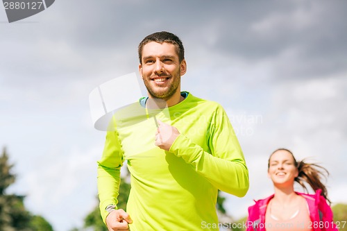 Image of smiling couple running outdoors