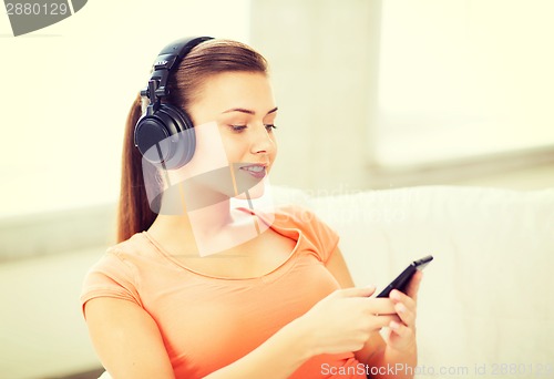 Image of woman with headphones and smartphone at home