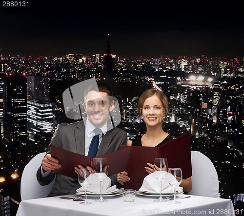 Image of smiling couple with menus at restaurant