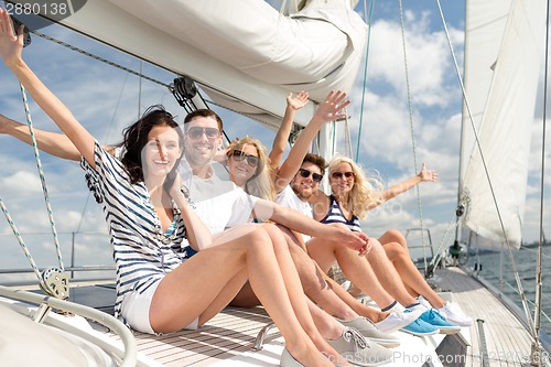 Image of smiling friends sitting on yacht deck and greeting