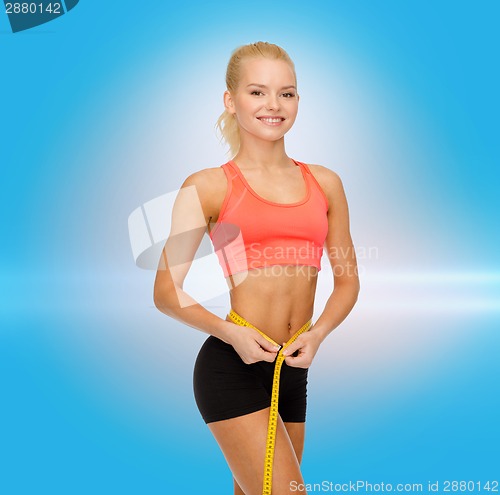 Image of smiling sporty woman with measuring tape