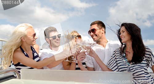 Image of smiling friends with glasses of champagne on yacht