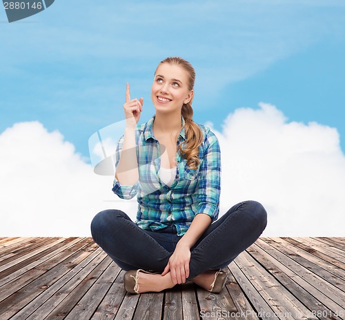 Image of smiling young woman pointing finger up